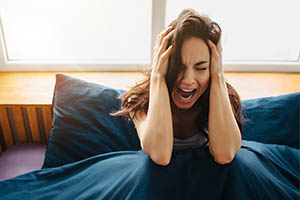 exploding head syndrome - woman holding head